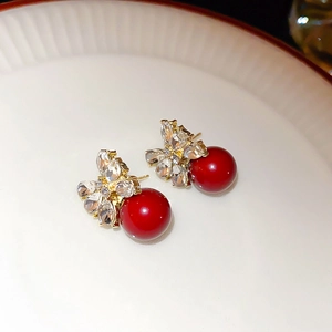 Detail von eleganten roten Perlenohrringen mit Strassblumen und goldener Schleifenverzierung