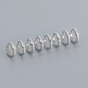 Detail view of four pairs of s925 silver hoop earrings with geometric crystal charms