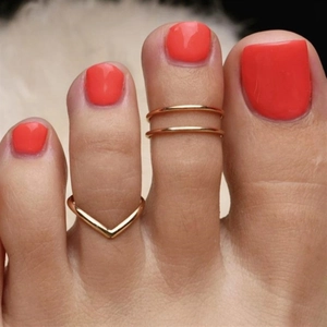 Macro detail of two minimalist gold toe rings in double-layer and V-shape geometric designs