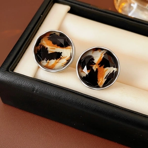 Close-up of leopard print round stud earrings with faceted inlay and silver trim