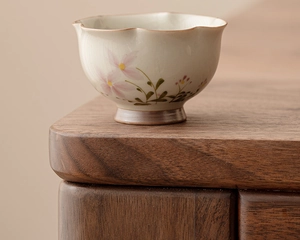 Macro shot of ceramic teacup featuring a petal-shaped rim and hand-painted floral details