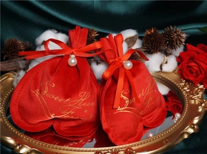 Detail of red heart-shaped velvet gift bag with pearl and satin ribbon on gold mirror tray