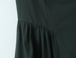 Close-up of dark green pleated fabric and fine stitching on a sexy backless dress