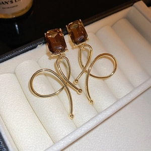 Detail of 18k gold plated drop earrings with amber rectangular stone in a jewelry box