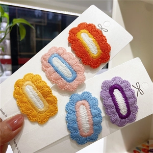 Close-up of five colorful embroidered flower hair clips on a white display card