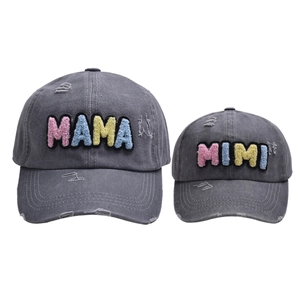 Détail de casquettes en denim délavé gris avec broderies MAMA et MIMI colorées
