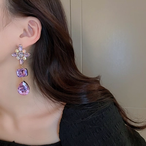 Close-up of elegant purple floral drop earrings with sparkling rhinestones on model