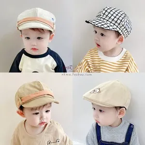 Detail of baby cotton beret caps in solid beige and classic black plaid pattern