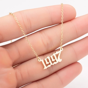 Detail of hand holding a 1997 gold stainless steel necklace with a gothic number pendant