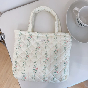 Macro shot of quilted cream floral tote bag with simple wish label and soft texture