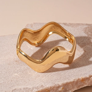 Close-up of golden irregular wavy bangle with polished mirror finish on stone