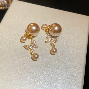 Nahaufnahme der goldenen Schmetterlings-Ohrstecker mit weißen Perlen und Zirkonia-Akzenten