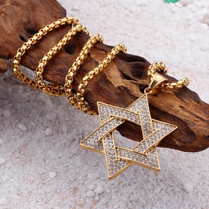 Detailed close-up of iced out hexagram star pendant on gold box chain over wood