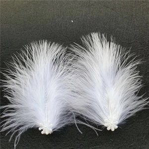 Eleganti fermagli per capelli in piuma bianca con piccole perle su sfondo di tessuto nero