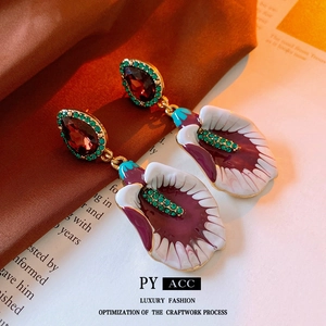 Detail of vintage calla lily earrings with purple enamel and red gemstones on silk