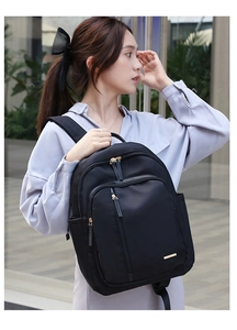 Detalle de mochila de tela Oxford negra con cremalleras doradas en estilo urbano