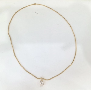 Detailed close-up of a pear-shaped zircon pendant with a golden bead chain necklace