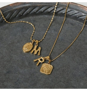 Macro detail of 18K gold plated bamboo letter pendants and embossed relief charms