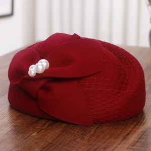Detail of burgundy wool pillbox hat with elegant mesh veil, bow and pearl accents