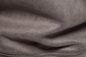 Macro du tissu en daim gris-brun montrant la texture fine et les détails de couture