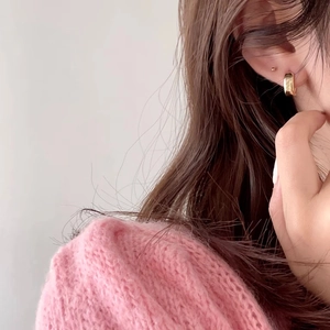 Close-up of chunky gold hoop earring worn with a soft pink mohair knit sweater