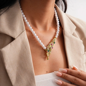 Detail of vintage flower pendant with pearls on a model wearing a beige blazer