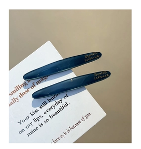 Close-up of two deep blue glossy French barrettes with gold Barrette La France text