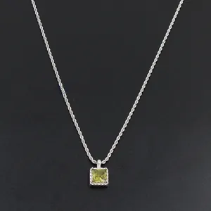 Détail d'un collier chaîne torsadée argentée avec pendentif en zircon vert carré