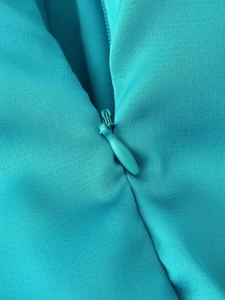 Detailed macro shot of a green satin dress featuring a concealed invisible zipper closure