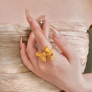 Detail of 18K gold bow-shaped openwork ring worn on hand with an elegant manicure