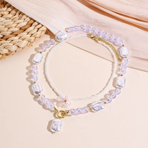 Close-up of double-layered baroque pearl necklace with purple beads and pink bow charm