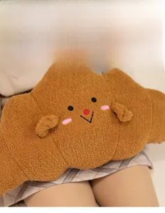 Detail of soft plush croissant pillow featuring embroidered smiley face and cozy texture