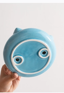 Detailed bottom view of the sky blue ceramic pet bowl showing smooth glaze and drain holes