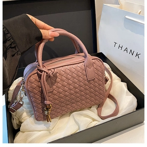 Detailed view of hand-woven leather Boston bag in smoky pink inside a premium gift box