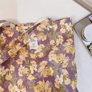Dettaglio della borsa in tela floreale viola con etichetta bianca tessuta sul davanti