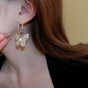 Macro shot of butterfly drop earrings with cubic zirconia and gold plating on model
