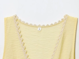 Detailed close-up of V-neckline with delicate lace trim on yellow sleeveless top