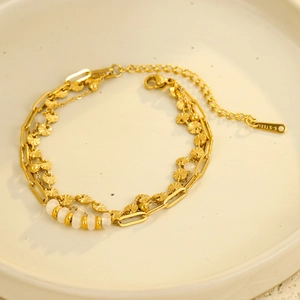 Gold-plated layered stainless steel bracelet with white beads and etched circular discs