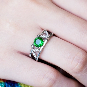 Close-up of a silver filigree ring with a brilliant round green gemstone and white diamonds