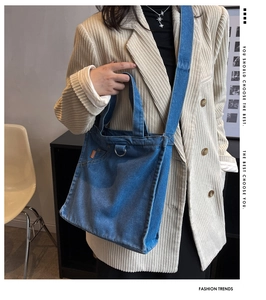 Detail of blue denim tote bag with adjustable shoulder strap on a fashion model
