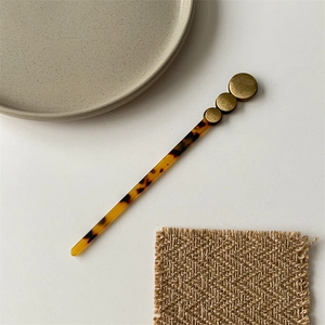 Detailed view of acetate hair pin with faux tortoise texture and brass metal discs