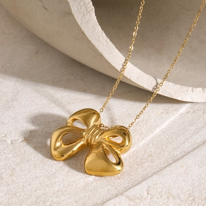 Macro shot of 18k gold butterfly bow pendant on a fine stainless steel chain