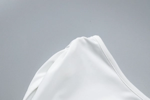 Detail of precise stitching and fabric texture on white sleeveless top shoulder