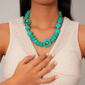 Detail of bohemian acrylic turquoise beads necklace with golden metal spacers on model