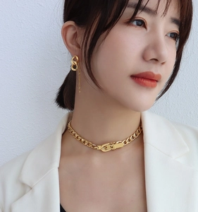 Detailed view of chunky gold chain necklace with buckle and tassel earrings on model