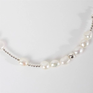 Detailed macro view of S925 sterling silver beads and baroque pearls on this minimalist bracelet