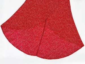 Detailed view of red polka dot dress fabric featuring ruffled hemline and lightweight texture