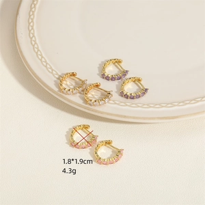 Trois paires de boucles d'oreilles créoles dorées avec zircons colorés sur plateau