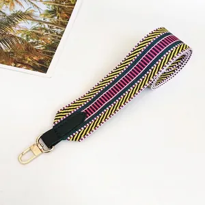 Detail of bohemian woven bag strap in yellow and green with gold metal swivel hook