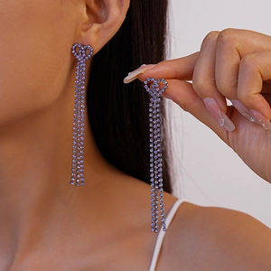 Macro shot of long purple tassel earrings with sparkling rhinestones and heart-shaped studs
